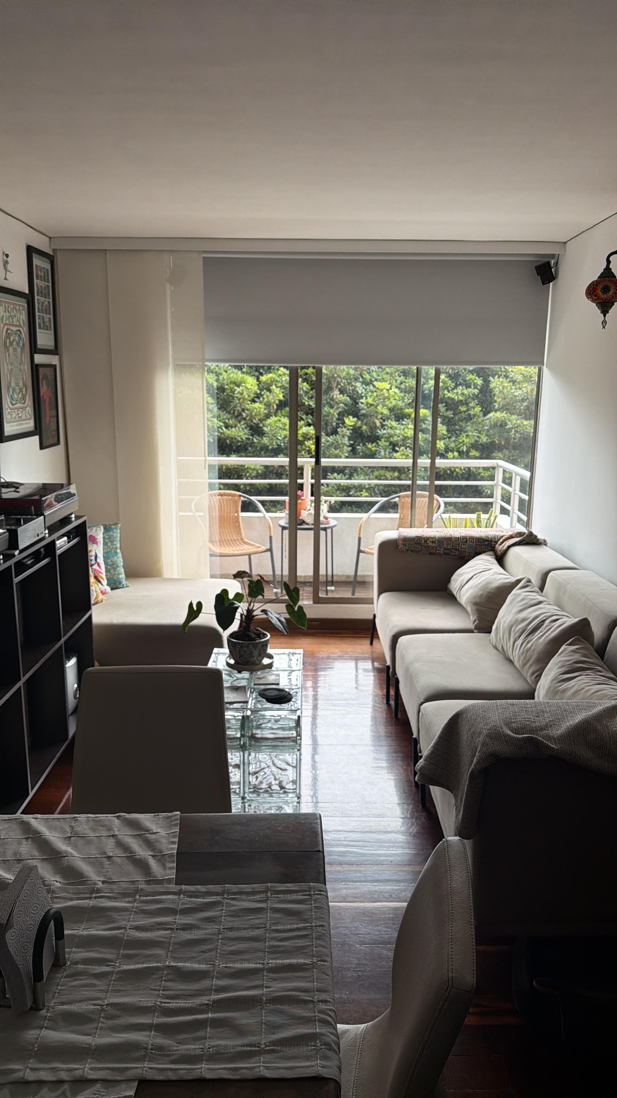 Cortina roller beige instalada en sala de apartamento con balcón en Bogotá